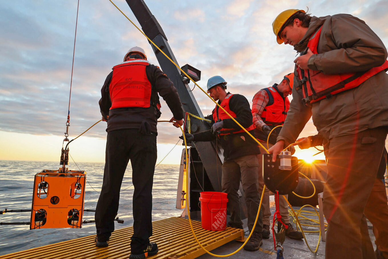 Quinlan Fahy (right) holds the clump weight while Stephen Jones and Joe Bevilacqua safely lower the ROV into the water.